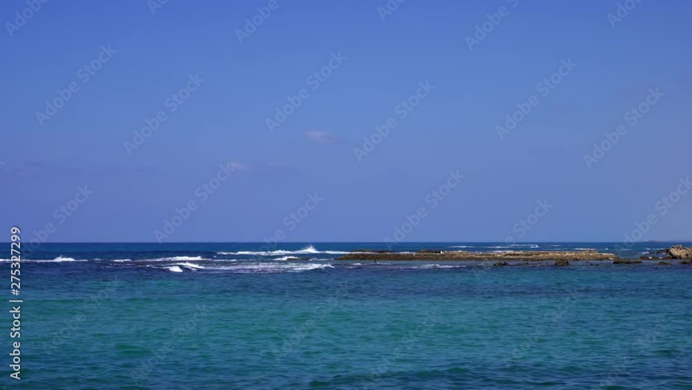 View of turquoise sea at sunny day. Panorama of seawater waves splashing against old moldy rocks at Mediterranean Sea View of turquoise sea at sunny day. Panorama of seawater waves splashing against old moldy rocks at Mediterranean Sea