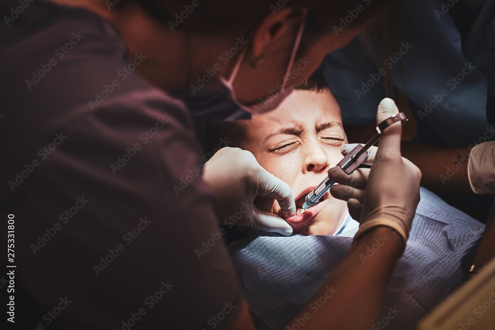 Little scared kid got an anastetic via syringe by expirienced dentist. Little scared kid got an anastetic via syringe by expirienced dentist.