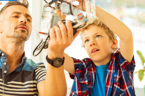 Nice pleasant father and son constructing a robot together