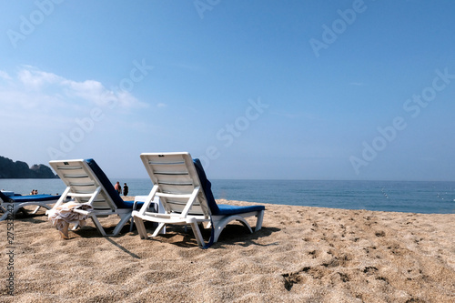 Fototapeta Naklejka Na Ścianę i Meble -  White sun loungers by the sea. Beautiful background. The concept of relaxation and rest. Paradise for tourists in the summer season.