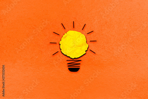 creative inspiration from yellow concept crumpled paper turn on light bulb metaphor for good idea concept on orange paper background / best solution think answer