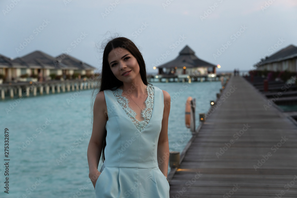 Beach vacation woman walking on bridge about bungalows luxury hotel in the background. Beach vacation woman walking on bridge about bungalows luxury hotel in the background.