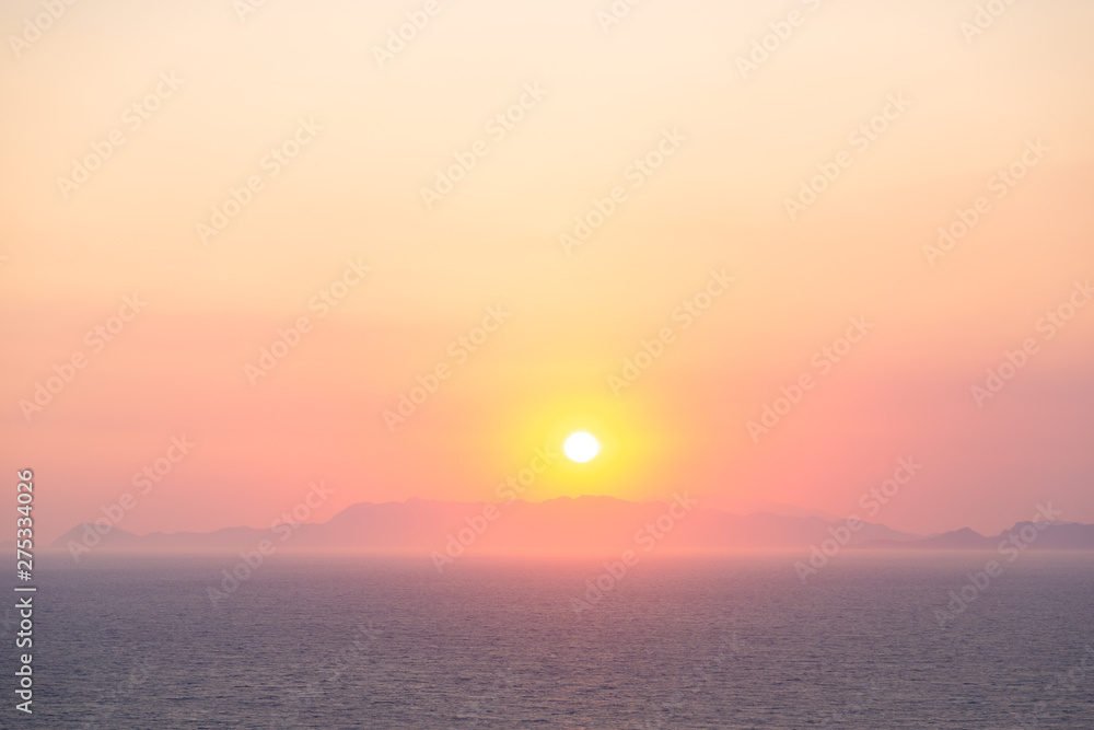 Sunset on the beach with distant mountains silhouettes