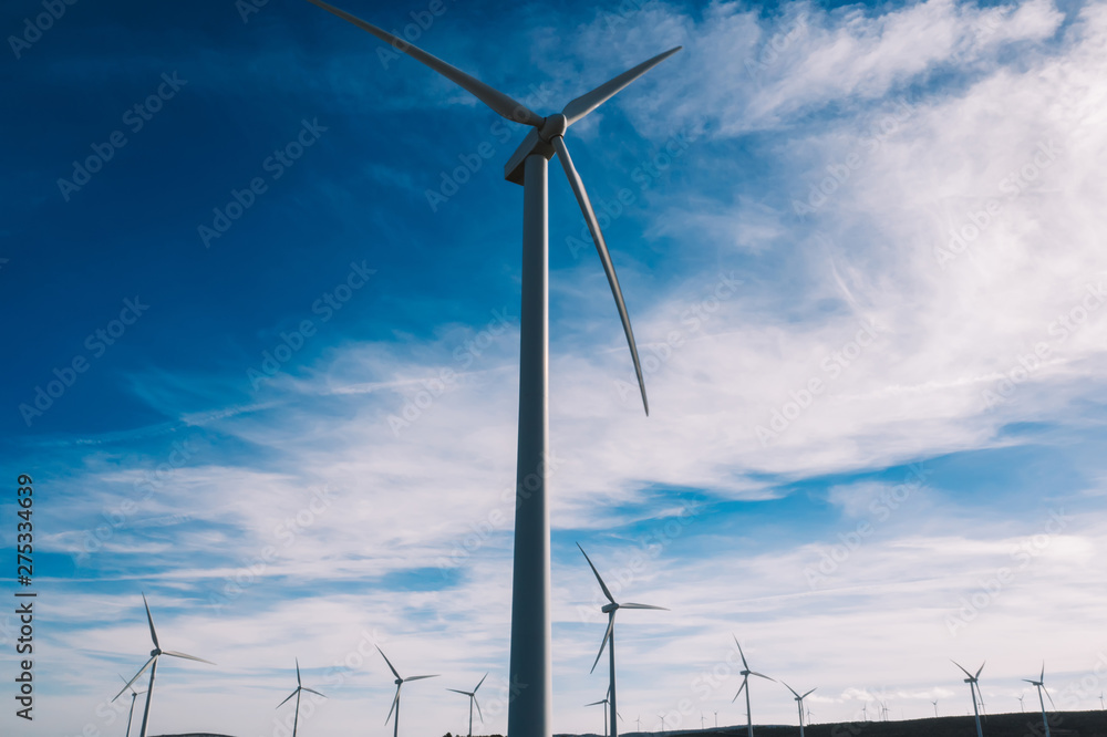 Below view of turbines propellers rotating from wind power producing clean eco energy and saving natural resources from climate change. Alternative electricity generation with friendly technology Below view of turbines propellers rotating from wind power producing clean eco energy and saving natural resources from climate change. Alternative electricity generation with friendly technology