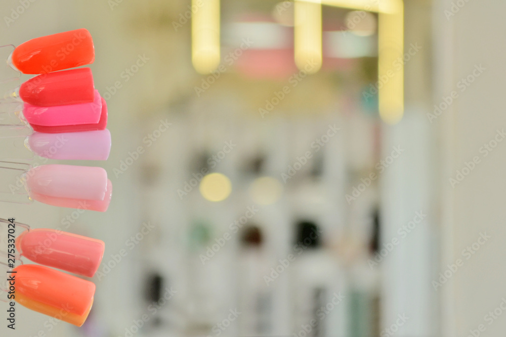 Palette with pink color samples of gel polish, against a background of blurry light bulbs and mirrors Palette with pink color samples of gel polish, against a background of blurry light bulbs and mirrors