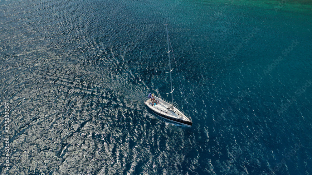 Naklejka premium Aerial drone photo of beautiful wooden deck sail boat cruising the deep blue sea of Mykonos island, Cyclades, Greece