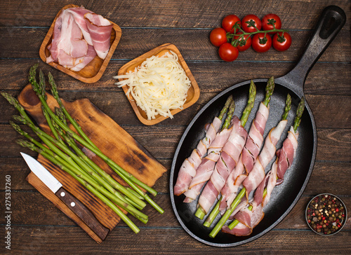Preparing bacon wrapped asparagus on wooden table.  Cooking asparagus. Ingredients for cooking on wooden background.