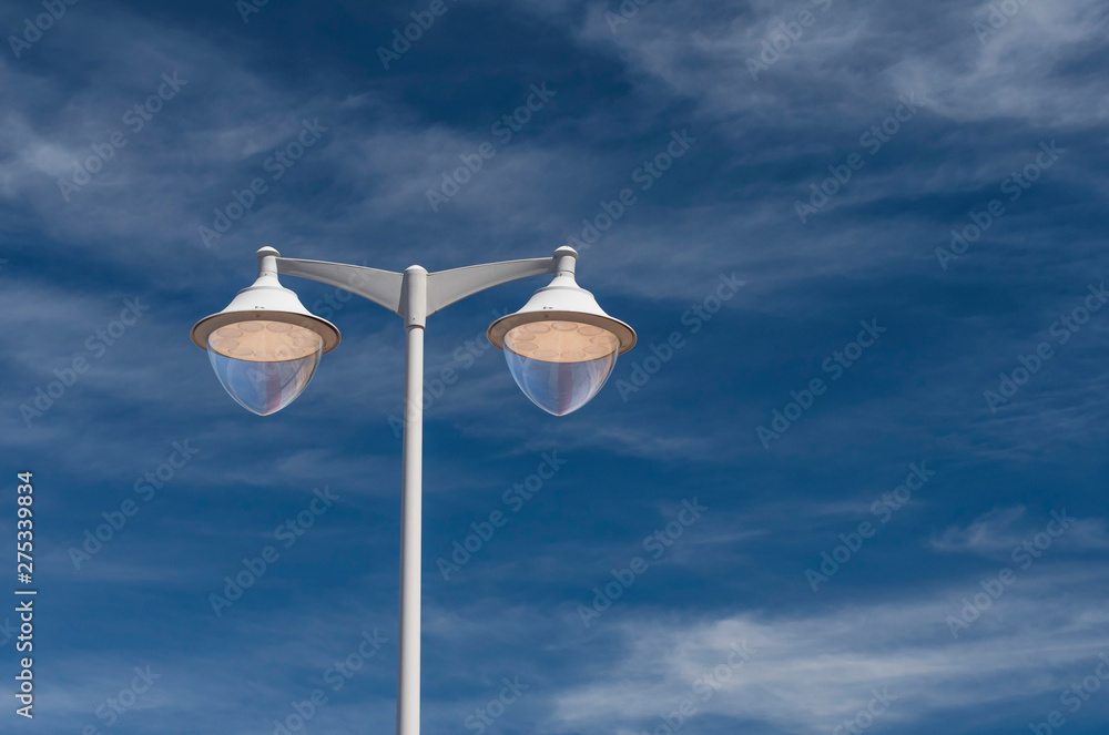 Freestanding street lamp in gray against a blue sky Freestanding street lamp in gray against a blue sky
