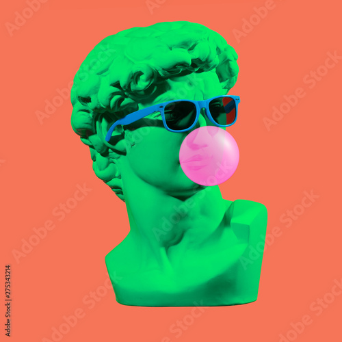 Statue. Earphone. Isolated. Gypsum statue of David's head. Man. Creative. Plaster statue of David's head in blue sunglasses. Minimal concept art.