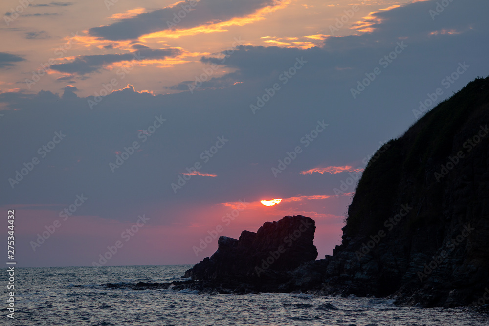 After rise, the sun clothed in the clouds above the rock. View from Sinemorets resort, Southern Black Sea Coast, Bulgaria.