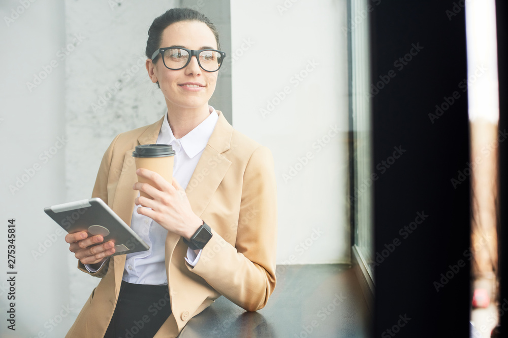 Mid age businesswoman working with a tablet during a coffee break in the office Mid age businesswoman working with a tablet during a coffee break in the office