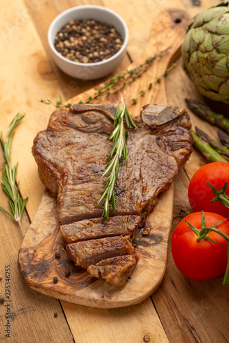 Marbled beef steak on a board with rosemary pepper, seasoning, and fresh vegetables on a wooden background, restaurant menu, gastronomy, tasty food. Restaurant service, verikalnoe photo, banner photo