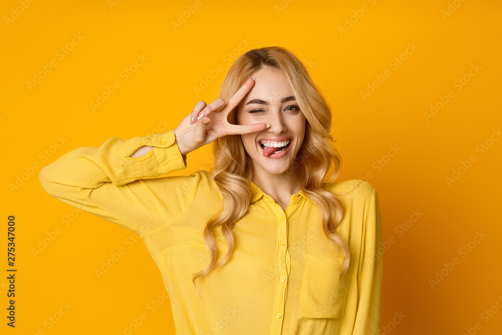 Pretty Girl Winking, Showing Tongue and Peace Gesture - obrazy, fototapety, plakaty 