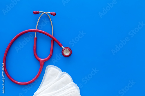 Gynaecologist and woman health concept with stethoscope and sanitary pads on blue background top view