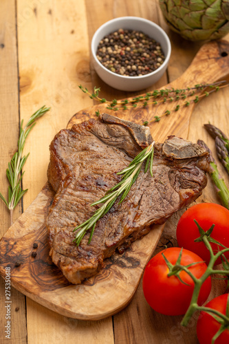 Marbled beef steak on a board with rosemary pepper, seasoning, and fresh vegetables on a wooden background, restaurant menu, gastronomy, tasty food. Restaurant service, verikalnoe photo, banner photo