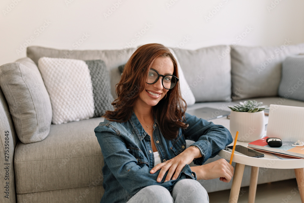 European happy adorable lady with curly hair sitting in modern office and working.