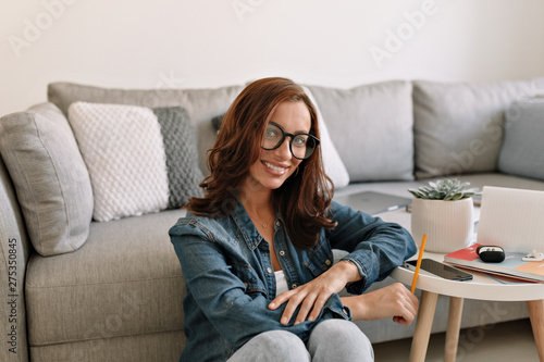 Obraz na płótnie European happy adorable lady with curly hair sitting in modern office and working. w salonie
