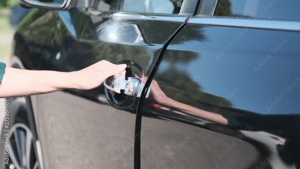a woman opens the door to her new black car. bought the car at the dealership a woman opens the door to her new black car. bought the car at the dealership