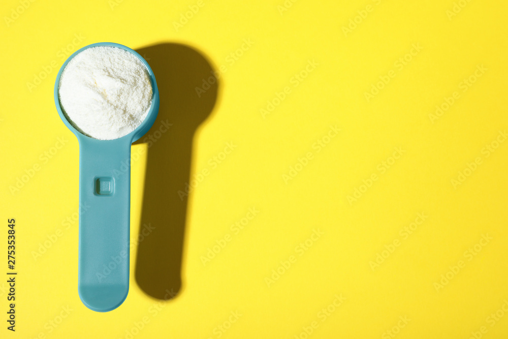 Scoop of protein powder on yellow background, top view with space for text Scoop of protein powder on yellow background, top view with space for text