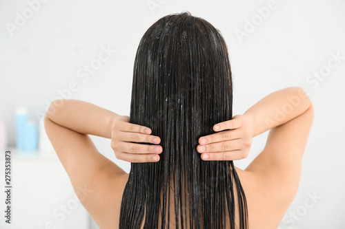 Woman applying hair conditioner in light bathroom photo