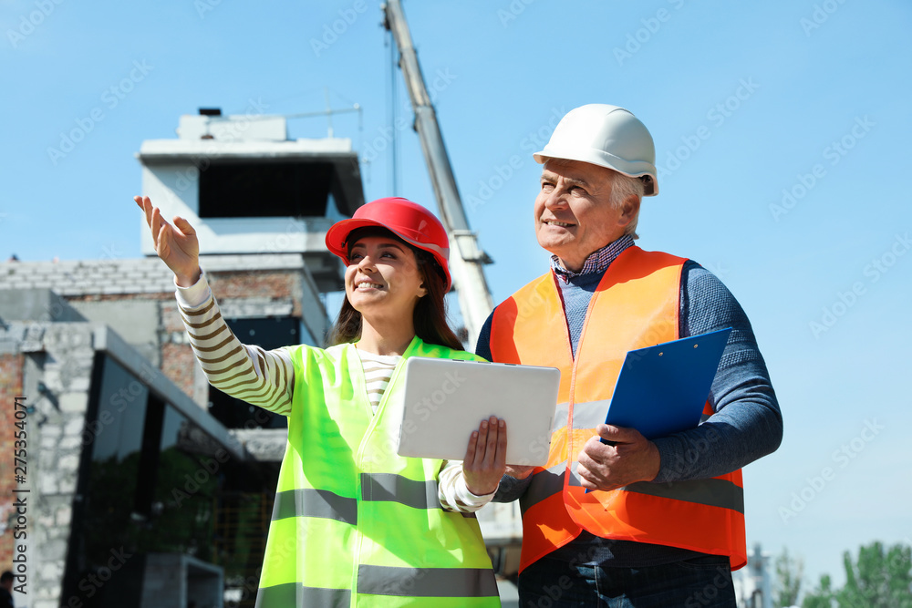 Professional engineer and foreman in safety equipment with tablet at construction site Professional engineer and foreman in safety equipment with tablet at construction site
