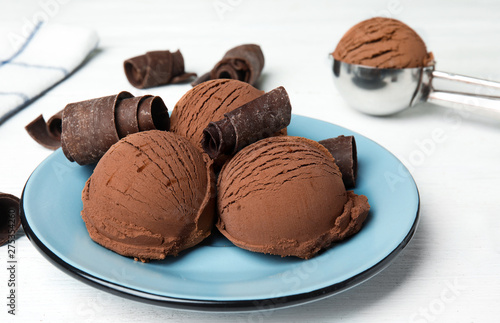 Plate of ice cream and chocolate curls on white wooden table