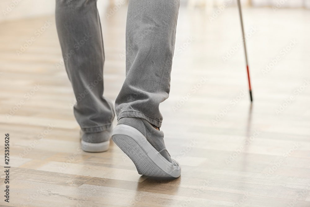 Blind person with long cane walking indoors, closeup Blind person with long cane walking indoors, closeup
