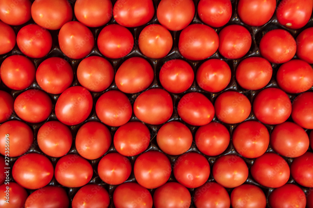 Fresh tomatoes are arranged and fill in roll and column between grid system in open package on stall in supermarket. Systematic tomatoes arrangement top view. Fresh tomatoes are arranged and fill in roll and column between grid system in open package on stall in supermarket. Systematic tomatoes arrangement top view.