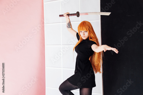 young woman in japanese anime cosplay, holding samurai sword. photo