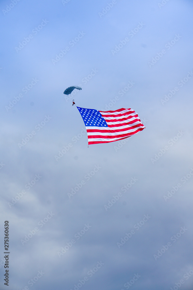 Naklejka premium person parachuting with american flag flying in wind