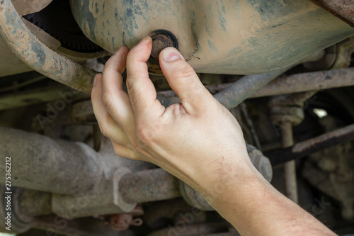 Foto Mechanic hand unscrews the cover of the engine crankcase to drain the waste oil