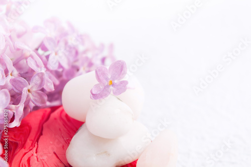 Spa and massage relaxation concept with white stones. red handmade soap and lilac flowers with copy space