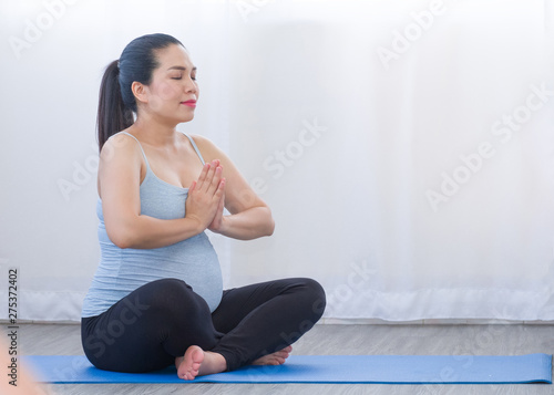 Asia Pregnant woman doing yoga exercise and meditation on the Yoga mat.