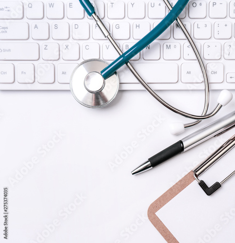 Stethoscope on keyboard on white table background. Online medical information treatment technology office concept, top view, flat lay, copy space