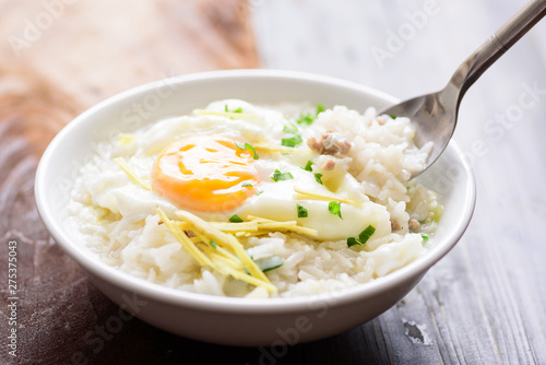 Thai rice soup or soft-boiled rice with pork and egg in the bowl with spoon for eating