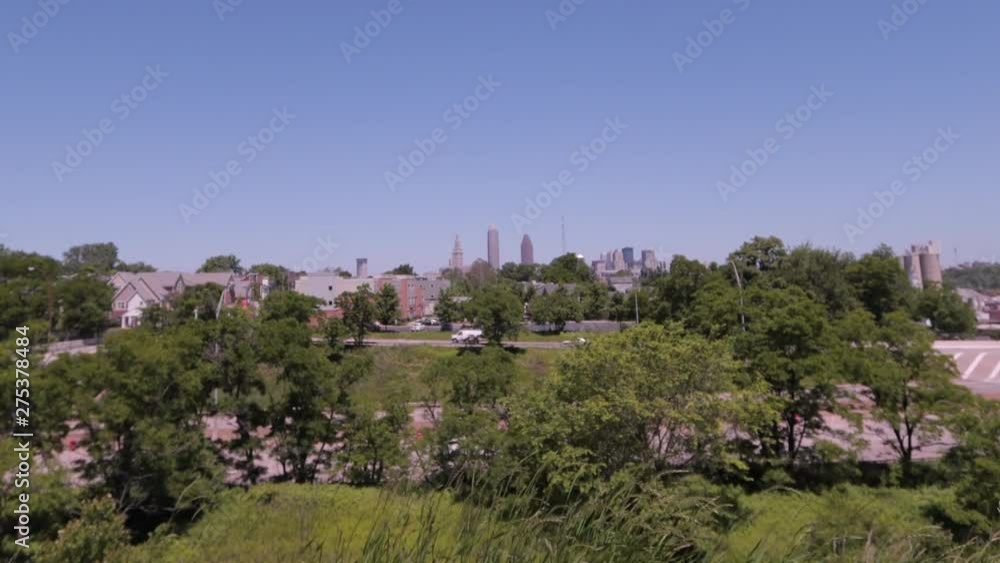 Cleveland, Ohio skyline as seen from the mounds in Tremont, a nearby neighborhood. The CLE big three building shine bright on a sunny day with blue skies. Cleveland, Ohio skyline as seen from the mounds in Tremont, a nearby neighborhood. The CLE big three building shine bright on a sunny day with blue skies.