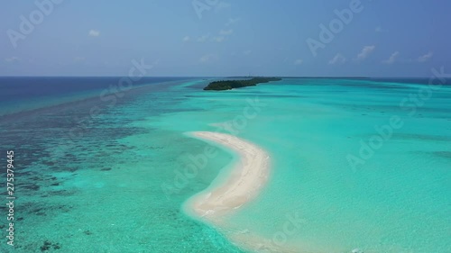 Drone flying over a small white sand beach island off the coast of a tropical island on the reef in the Maldives photo