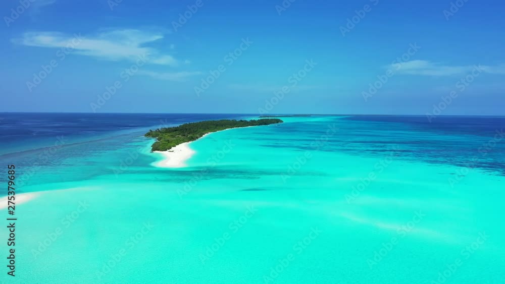 Distant view of a whole tropical island on the reef in the Maldives with an elongated white sand peninsula extending from the tip Distant view of a whole tropical island on the reef in the Maldives with an elongated white sand peninsula extending from the tip