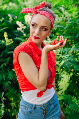Beautiful young pin up girl with bright make up and fresh natural strawberry.