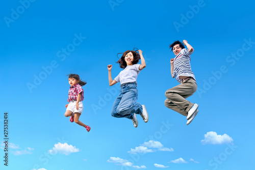 青空を背景に親子一緒にジャンプする家族。絆、愛情、幸せ、飛躍、未来イメージ