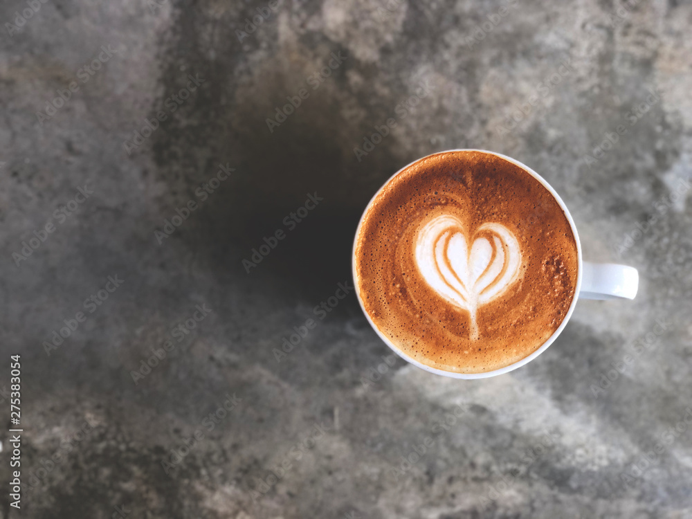 heart love piccolo  latte art in white cup on cement floor with natural light , vintage style and copy space.