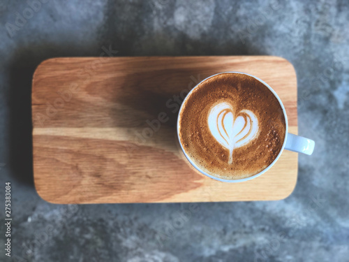 heart love piccolo latte art in white cup on wooden tray and cement floor with natural light , vintage style and copy space.