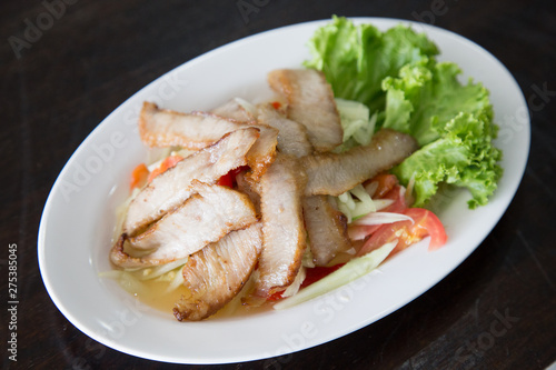 Sliced pork roasted Thai style with green salad on white plate