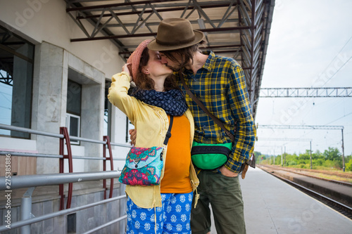 A couple of young travelers, man and woman, kissing each other on empty railway station.