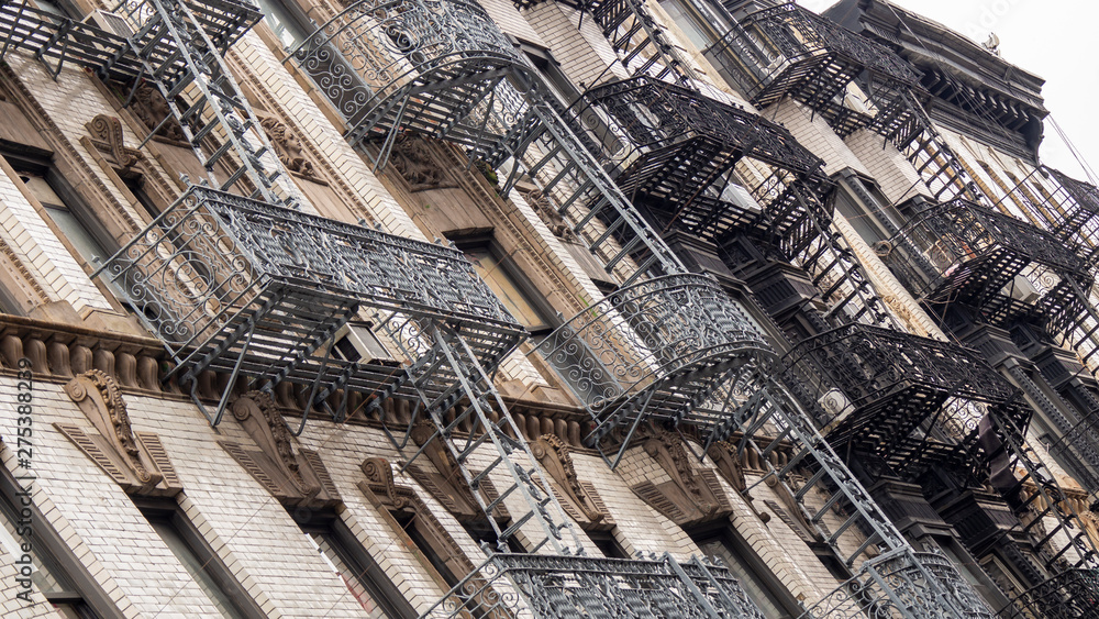 Naklejka premium Facades of historic buildings in the Soho district of New York. The characteristic iron safety stairs on the facades