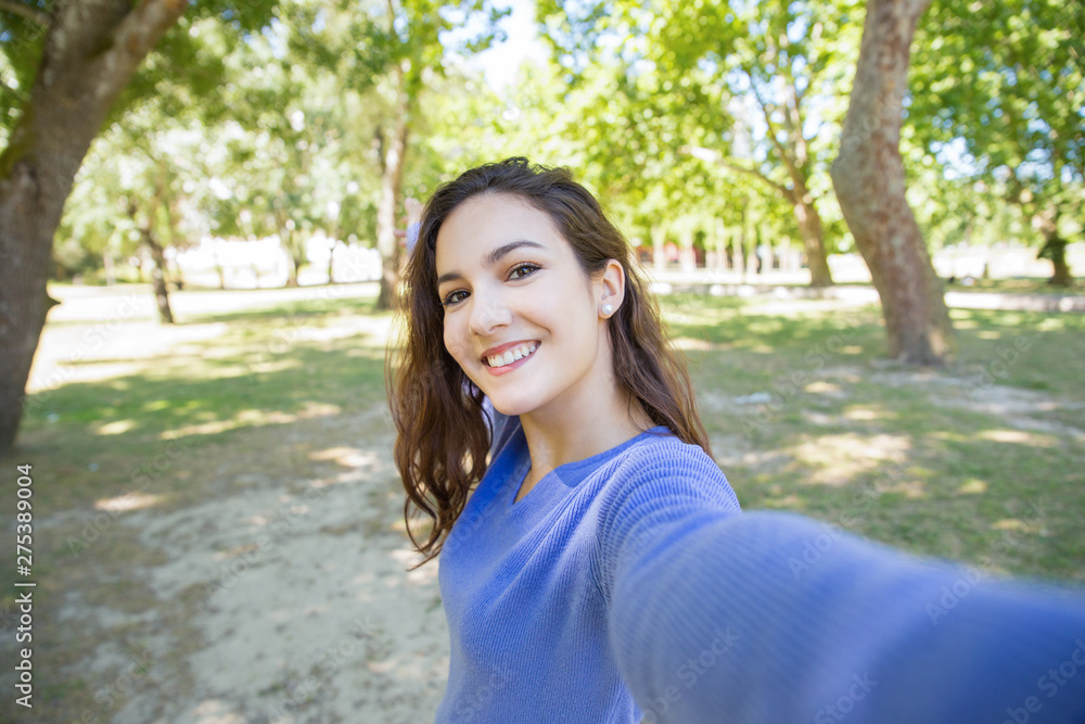 Happy young woman in blue sweater talking selfie in park. Carefree girl with wavy hair having fun alone in summer park. Environment concept Happy young woman in blue sweater talking selfie in park. Carefree girl with wavy hair having fun alone in summer park. Environment concept