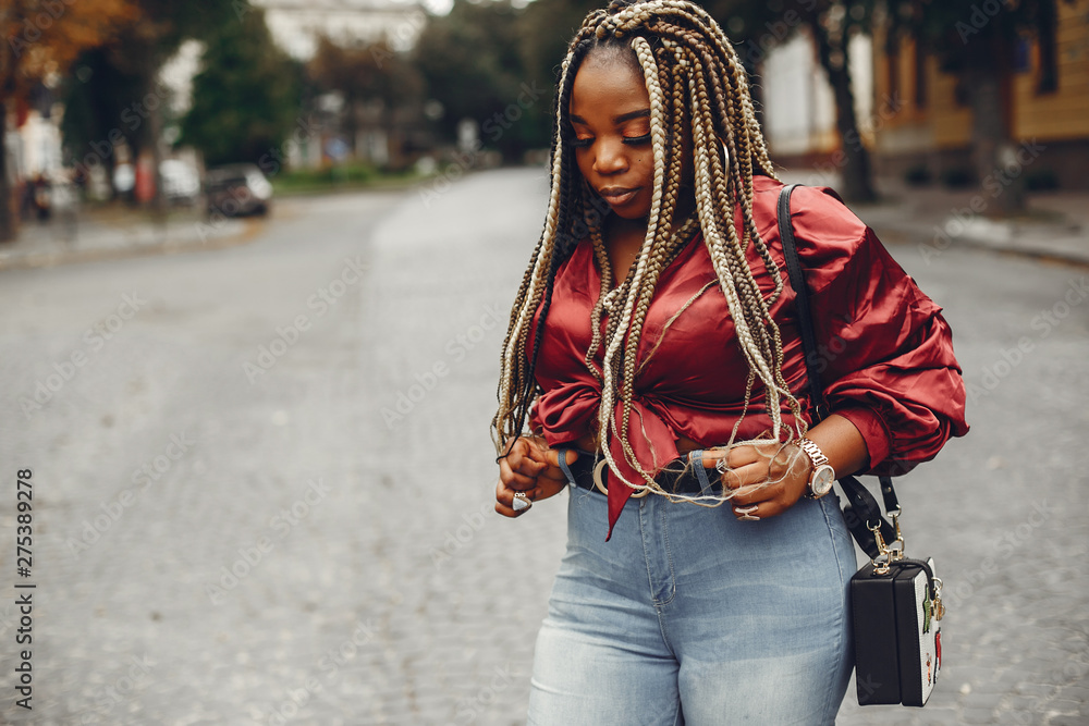 Cute black woman have fun in a city. Beautiful black girl in a red blouse