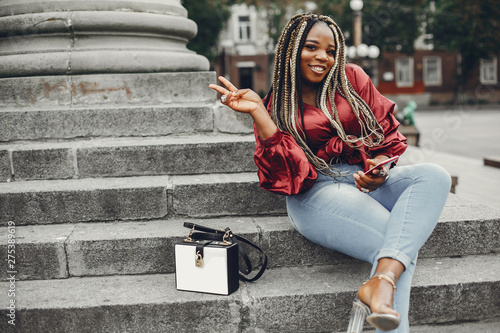 Cute black woman have fun in a city. Beautiful black girl in a red blouse