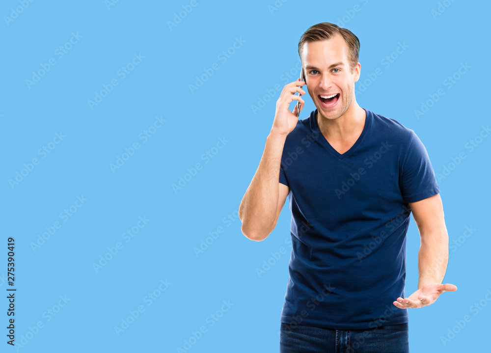 Very happy excited young man in blue casual clothing talking on smart phone, over blue color background. Very happy excited young man in blue casual clothing talking on smart phone, over blue color background.
