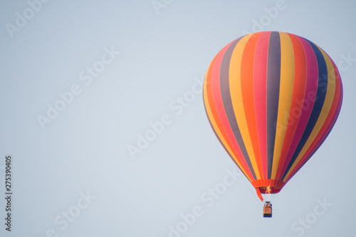 Colorful hot air balloon moving up in blue sky.